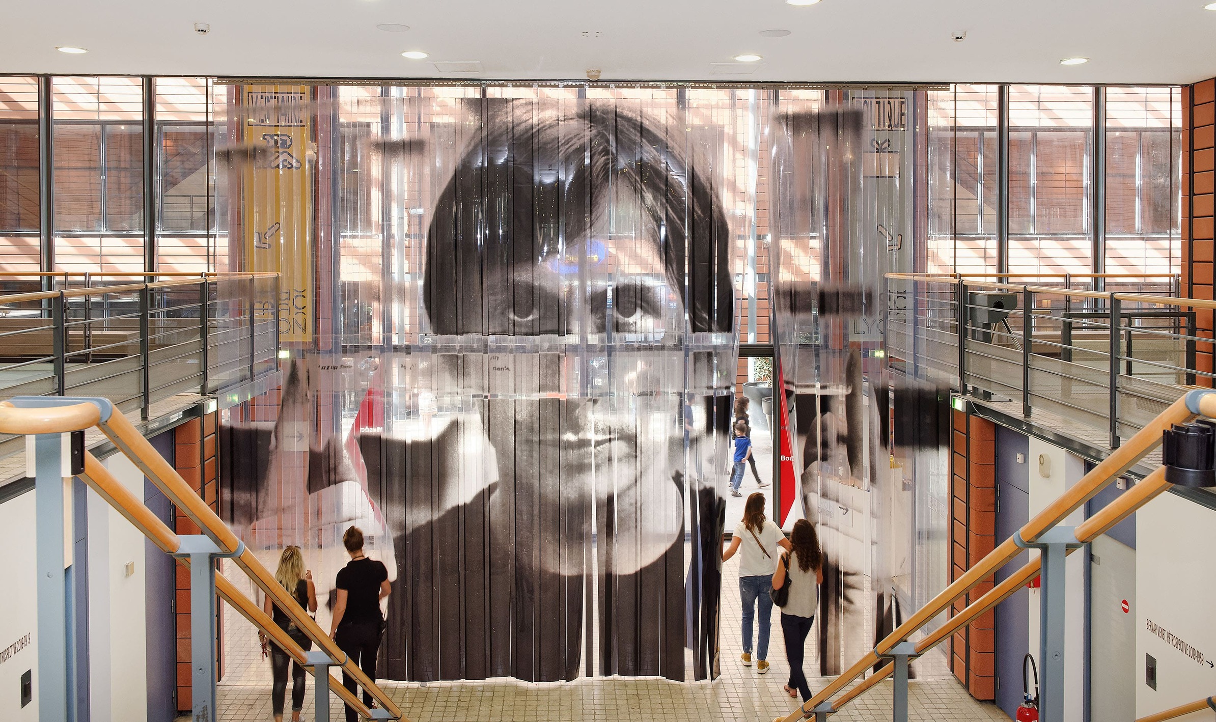 Visiteur franchissant un grand rideau à lanières PVC à l'entrée d'une exposition